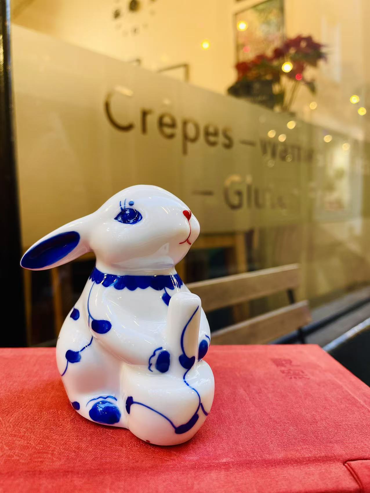 Seated rabbit with a swept-back ear, photographed on the original red table