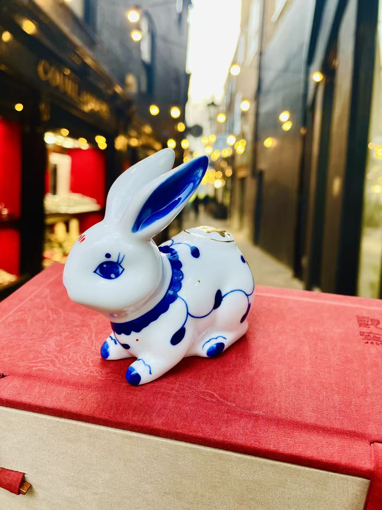Crouching rabbit with a blue eye and ear, photographed on the original red table